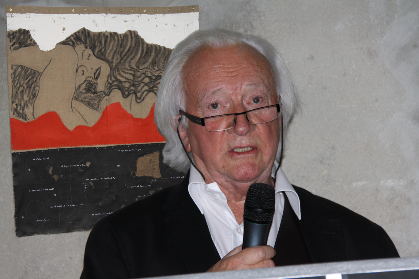Michel Degand lors du vernissage (en arrière plan l’œuvre référencée pour l’affiche de l’exposition). 