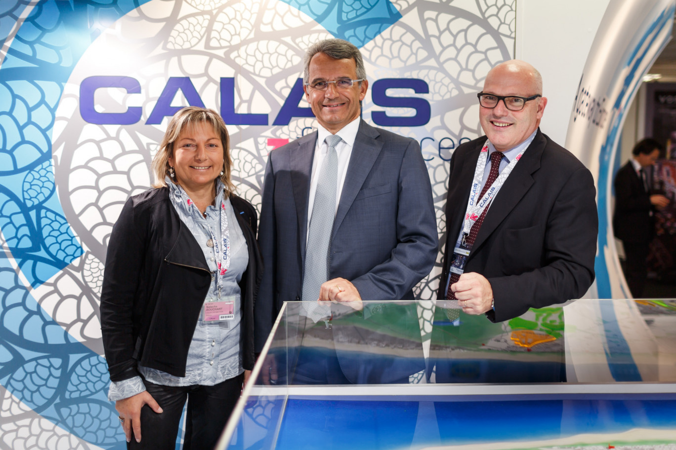 Sur le stand de Calais, au MAPIC de Cannes, au moment de la signature. De G. à D. : Mme Natacha Bouchart, sénateur-maire de Calais, MM. Denis Akriche, P.-D. G. d'Armatis et Didier Caudard-Breille, président de DCB.
