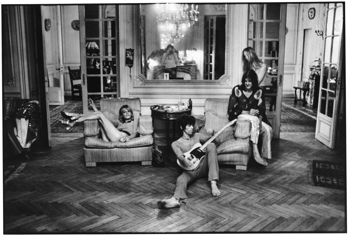 De gauche à droite : Anita Pallenberg, Keith Richards (avec la guitare offerte par Eric Clapton), Gram Parsons et sa compagne Gretchen Burrell, dans le salon de la villa Nellcote. On distingue Dominique Tarlé dans le reflet du miroir, 1971. © Dominique Tarlé