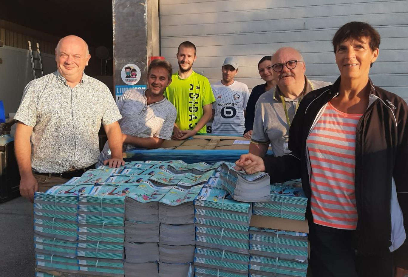 Olivier Thierry (à gauche), gérant fondateur de "100% bons plans", et une partie de son équipe de distributeurs posent devant la palette de magazines, tout juste sortis de chez l'imprimeur.