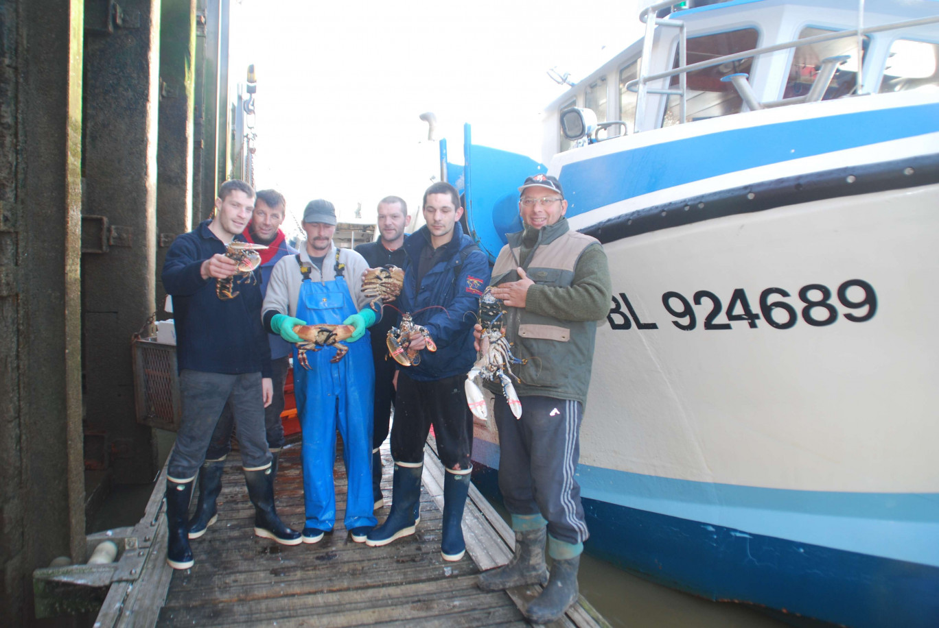 Jean-François Baillet (à droite) et son équipage devant leur embarcation amarrée au port de Boulogne-sur-Mer.