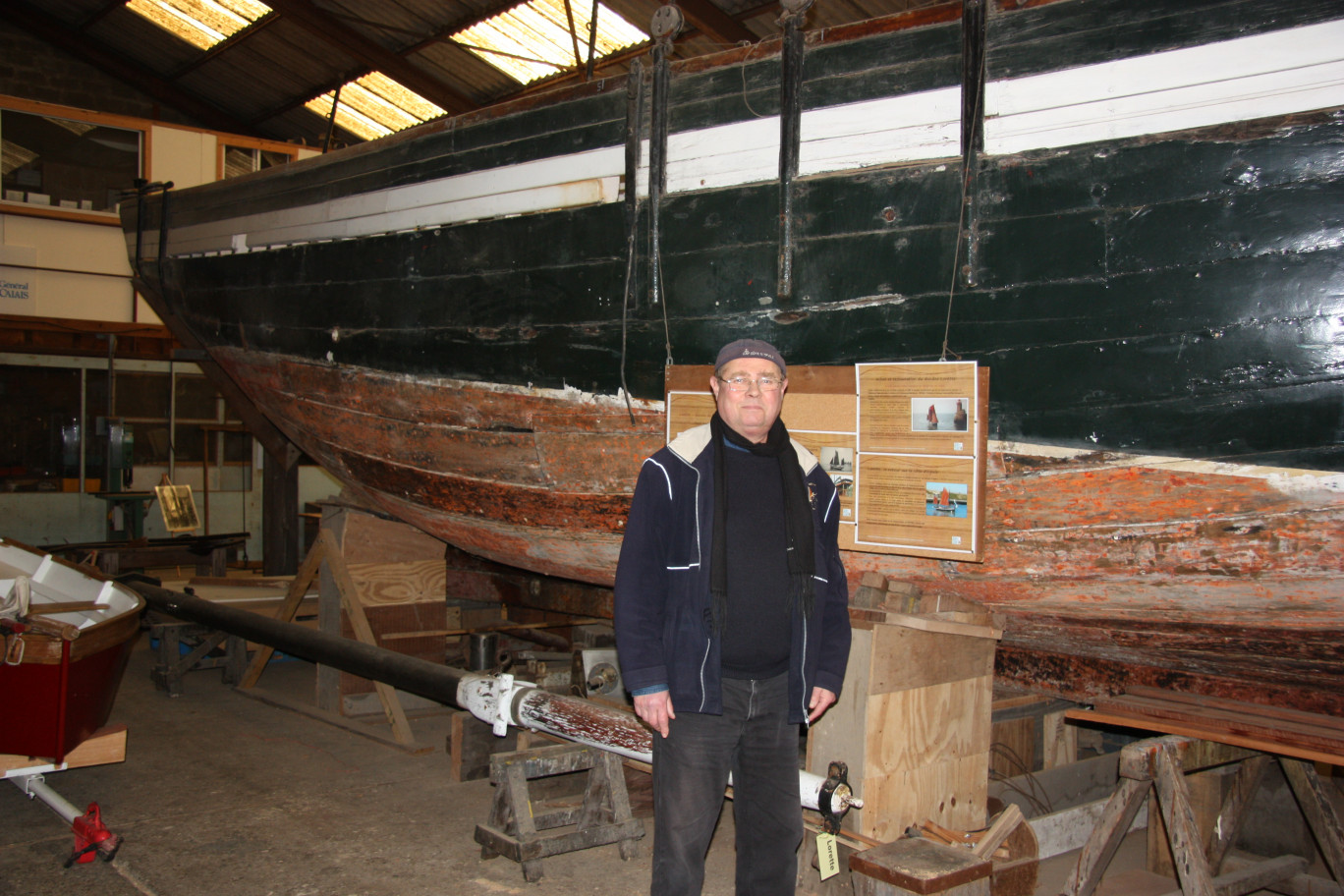 Marcel Charpentier dans les ateliers calaisiens de la FRCPM devant le dundee Lorette, le plus ancien voilier navigant du Nord-Pas de Calais pour lequel un appel aux dons afin de favoriser sa rénovation a été lancé.