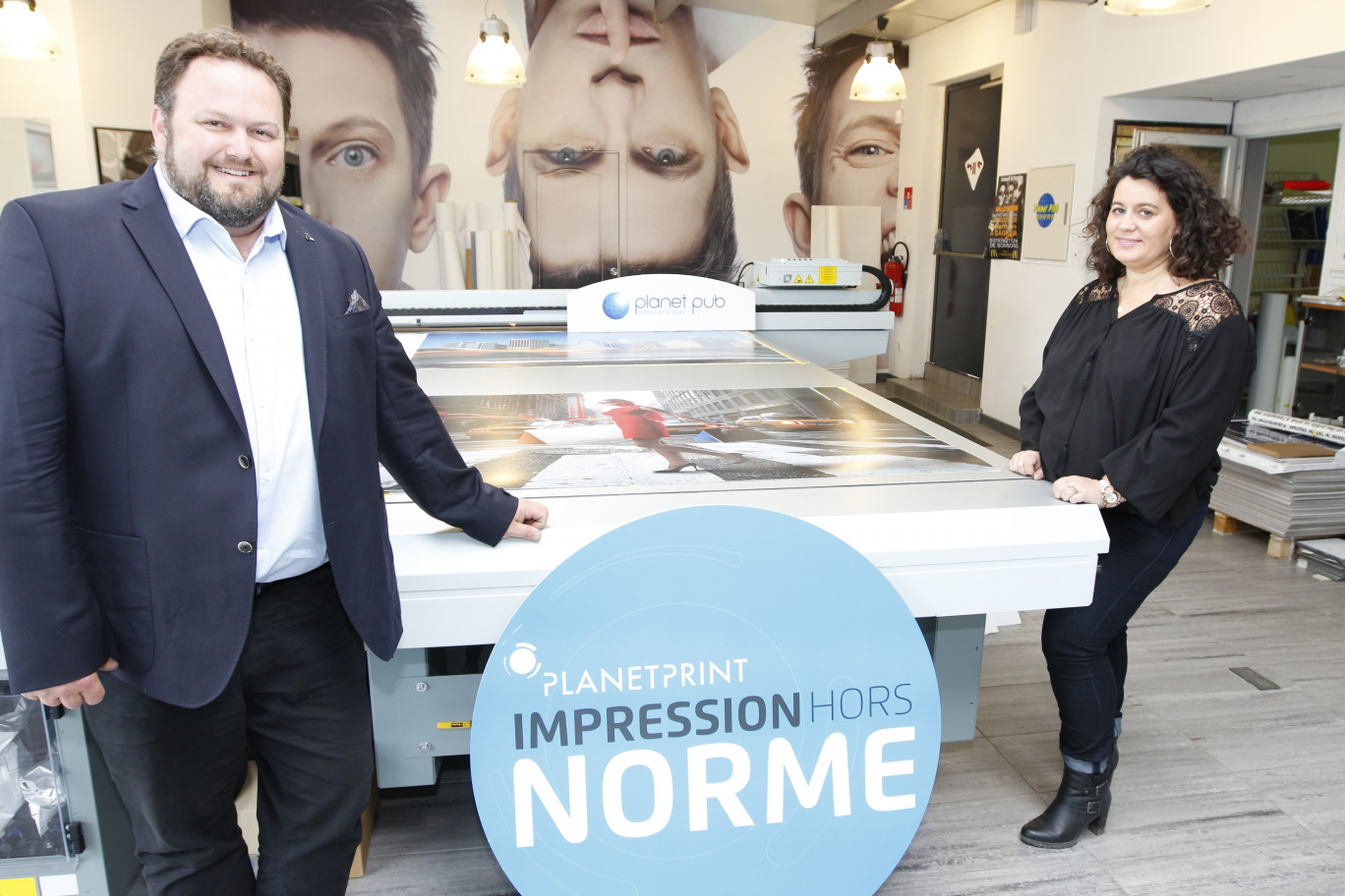 Frédéric et Mylène Mores posent devant leur dernière acquisition, une table d’impression en très grand format (3 m x 2,5 m) et multi support.