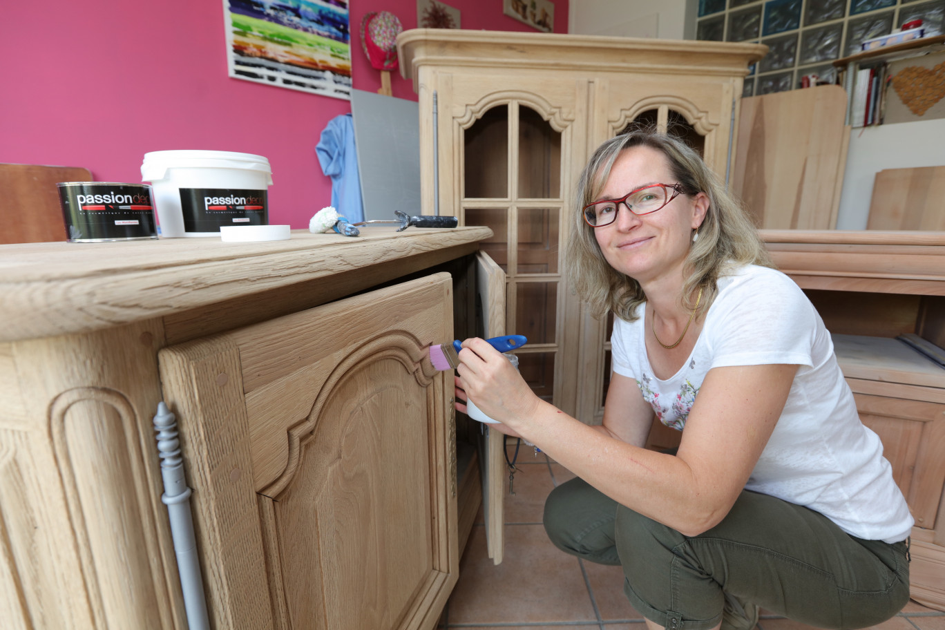 Isabelle Vernier est en train de travailler sur les meubles d’un de ses clients. D’un style rustique, elle va les passer à un style beaucoup plus moderne en ajoutant quelques touches de couleur. 